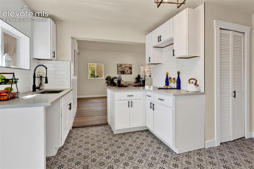 Image 14 of 26: Kitchen featuring patterned floor tiles, white cabinetry with matte black h