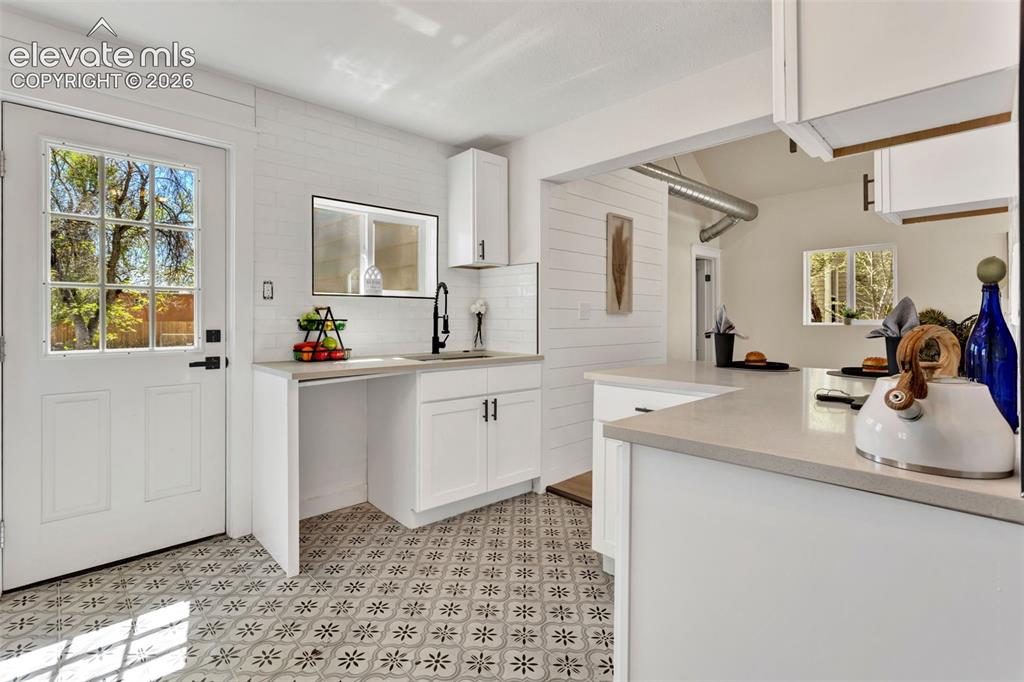 Image 15 of 26: Kitchen featuring patterned floor tile, white shaker cabinetry, light-toned