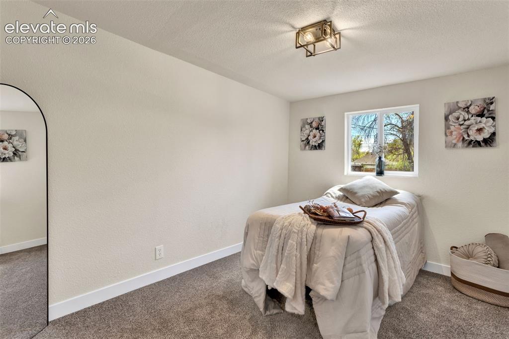 Image 19 of 26: Room featuring textured walls, a single window, and a flush-mount light fix