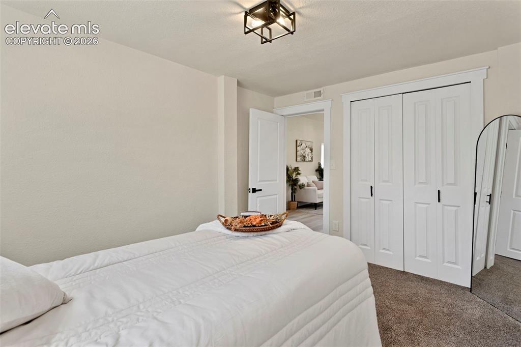 Image 20 of 26: Bedroom featuring neutral wall paint, carpet flooring, a white bi-fold clos