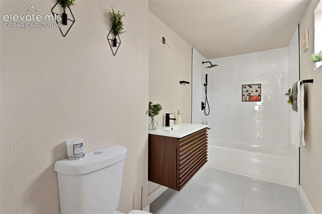 Image 21 of 26: Modern bathroom featuring a floating wood-slat vanity with a white countert