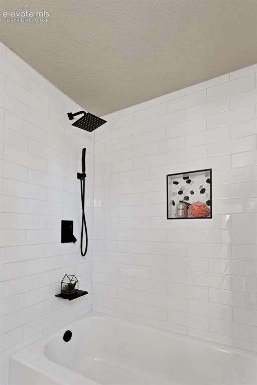 Image 22 of 26: Bathtub and shower combination featuring white subway tile surround