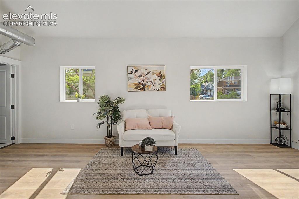 Image 23 of 26: Spacious interior featuring wood-finish flooring, white walls, and two wind