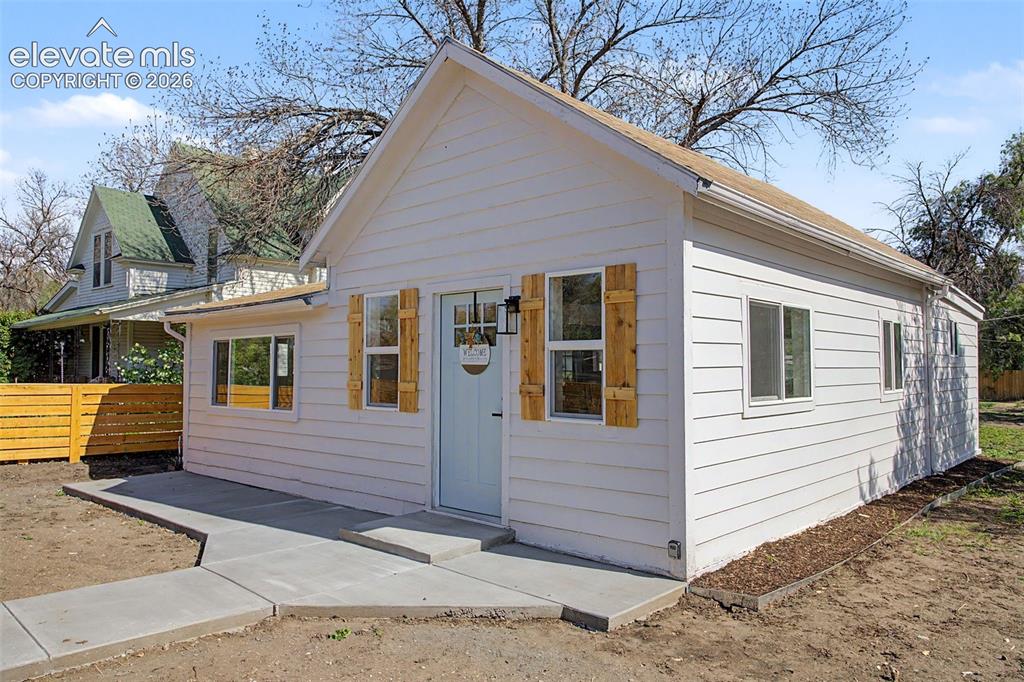 Image 3 of 26: White siding exterior with a light blue entry door