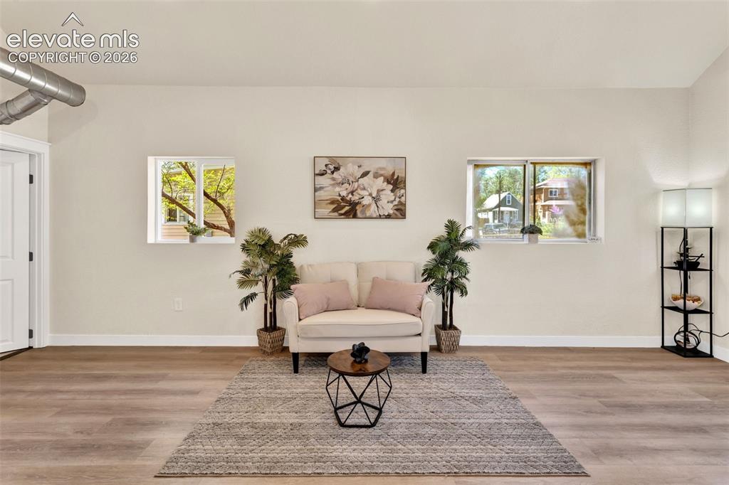 Image 9 of 26: Expansive room with wood-finish flooring and light-toned walls
