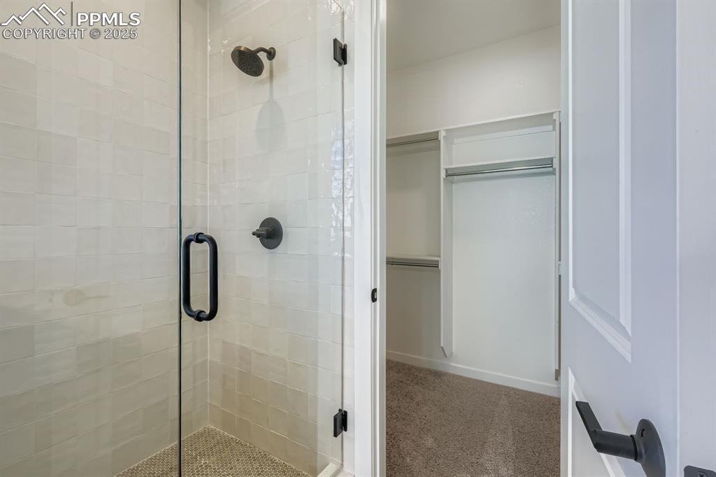 Image 14 of 27: Full bath with carpet floors, a shower stall, and a walk in closet