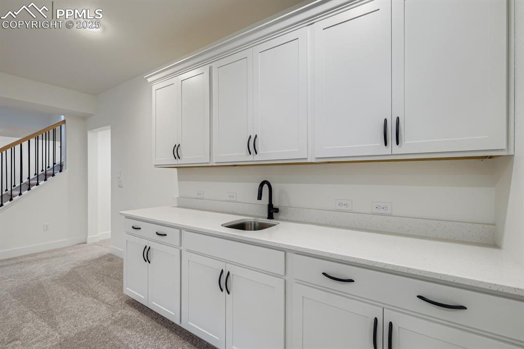 Image 18 of 27: Kitchen featuring white cabinetry, light carpet, light stone counters, and