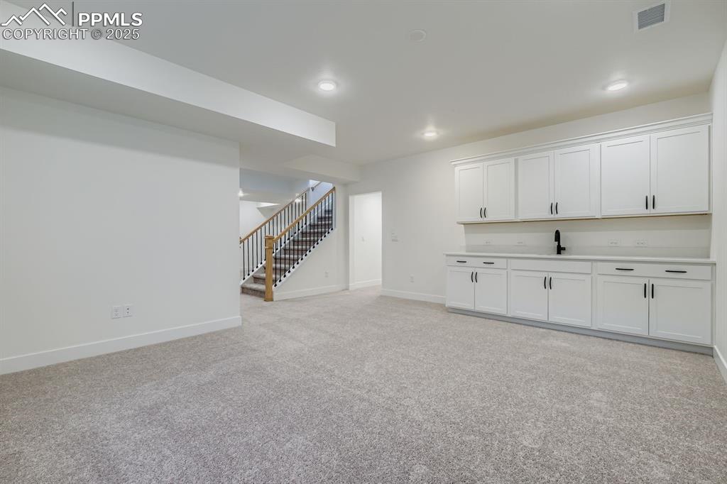 Image 22 of 27: Basement with stairway, light carpet, and recessed lighting