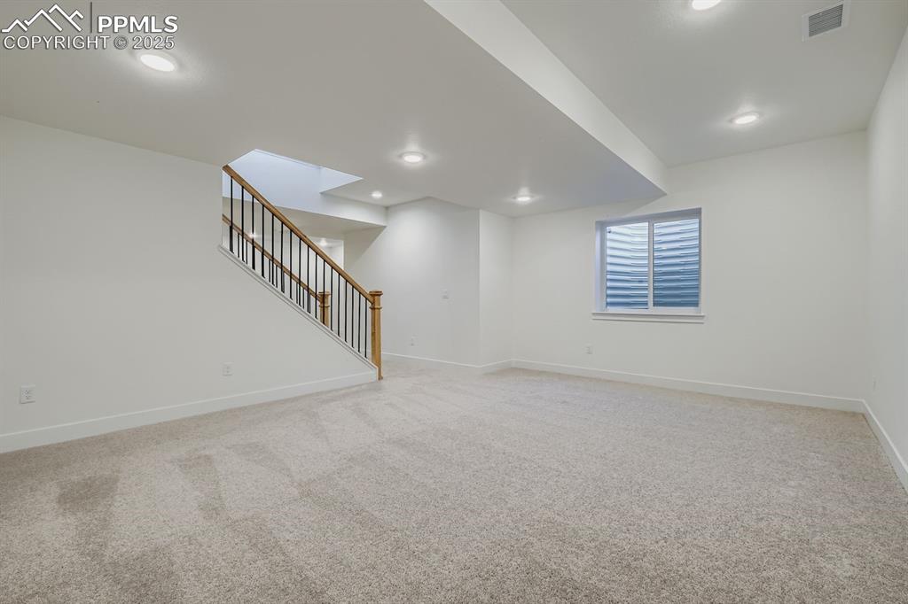 Image 23 of 27: Basement with light carpet, stairs, and recessed lighting