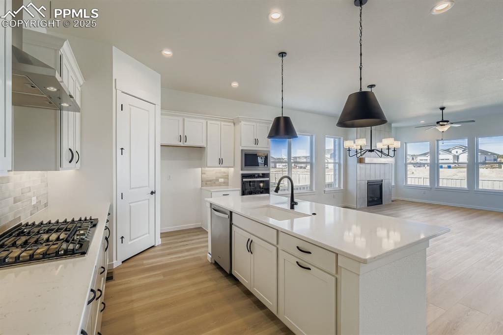 Image 8 of 27: Kitchen featuring backsplash, light wood-type flooring, white cabinets, rec