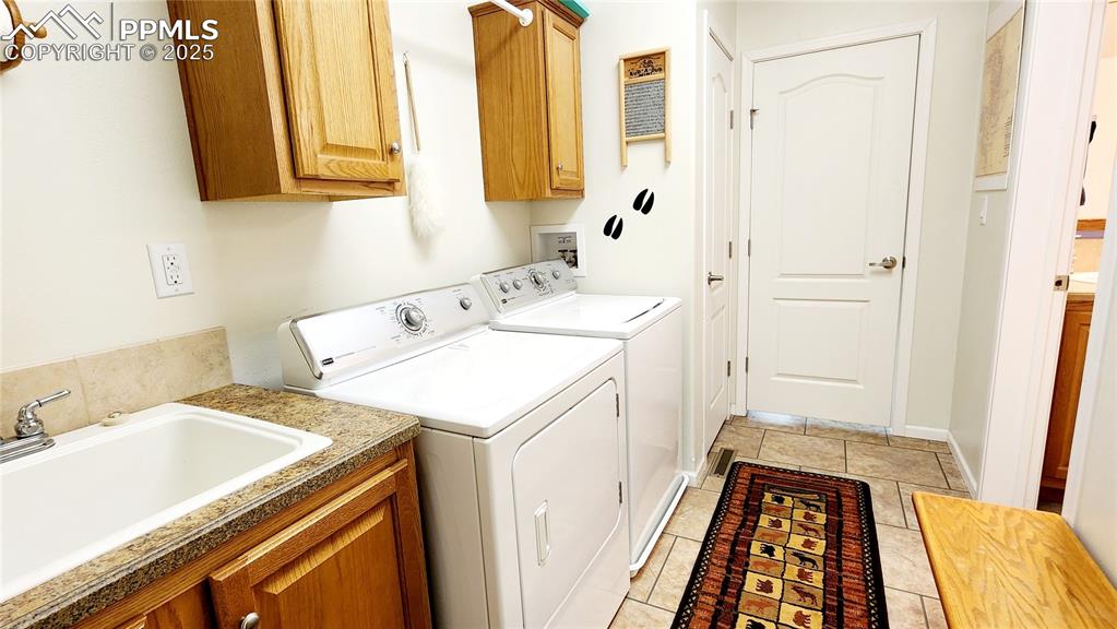 Image 27 of 50: large laundry area with utility sink and cabinets for storage