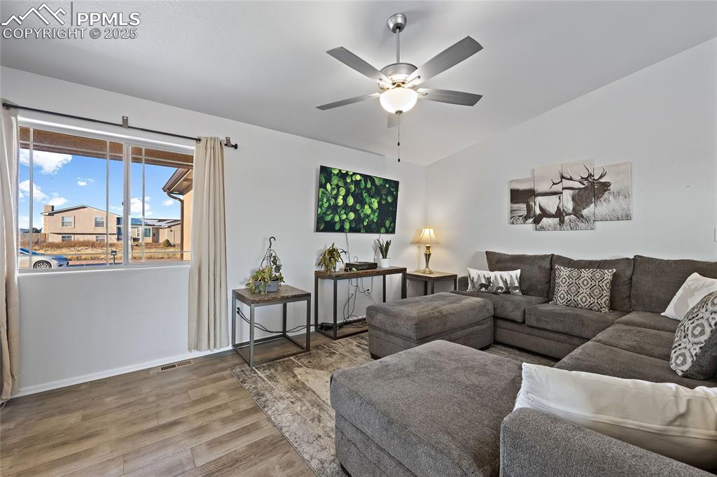 Image 7 of 36: Living area featuring wood finished floors, a ceiling fan, baseboards, and