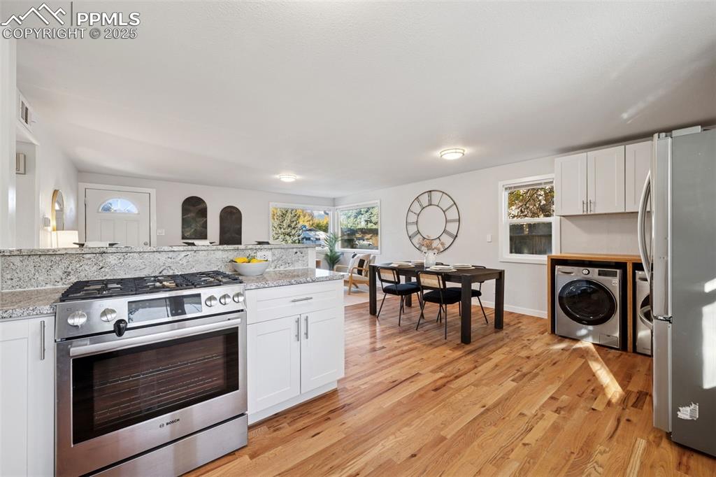Image 14 of 20: Kitchen featuring stainless steel appliances, washer / dryer, white cabinet