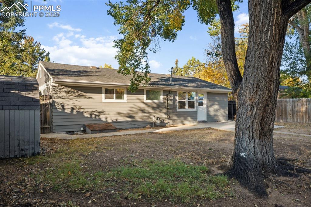 Image 6 of 20: Back of property featuring a shingled roof and a shed