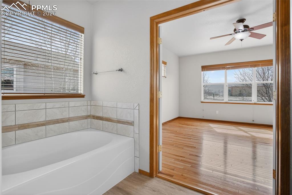 Image 12 of 22: Full bath featuring a ceiling fan, light wood finished floors, and a garden