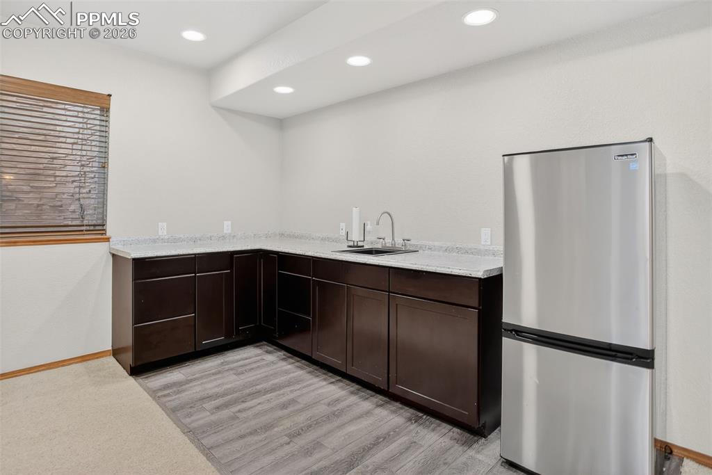 Image 16 of 22: Bar area featuring freestanding refrigerator, dark wood finish cabinets, li