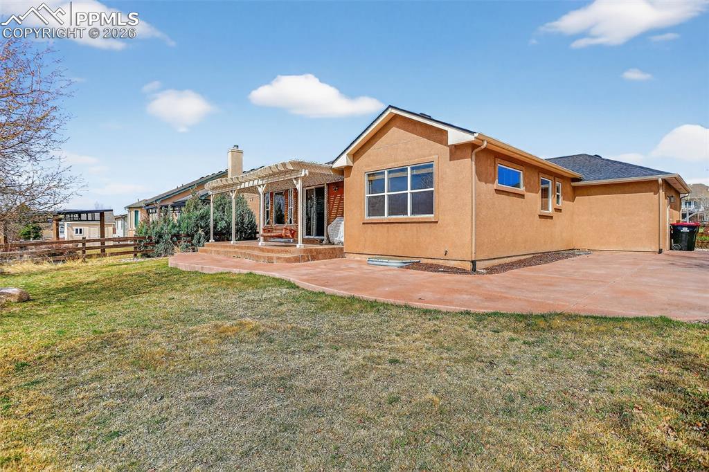 Image 21 of 22: Rear view of house featuring stucco siding, a patio, a pergola, and a chimn