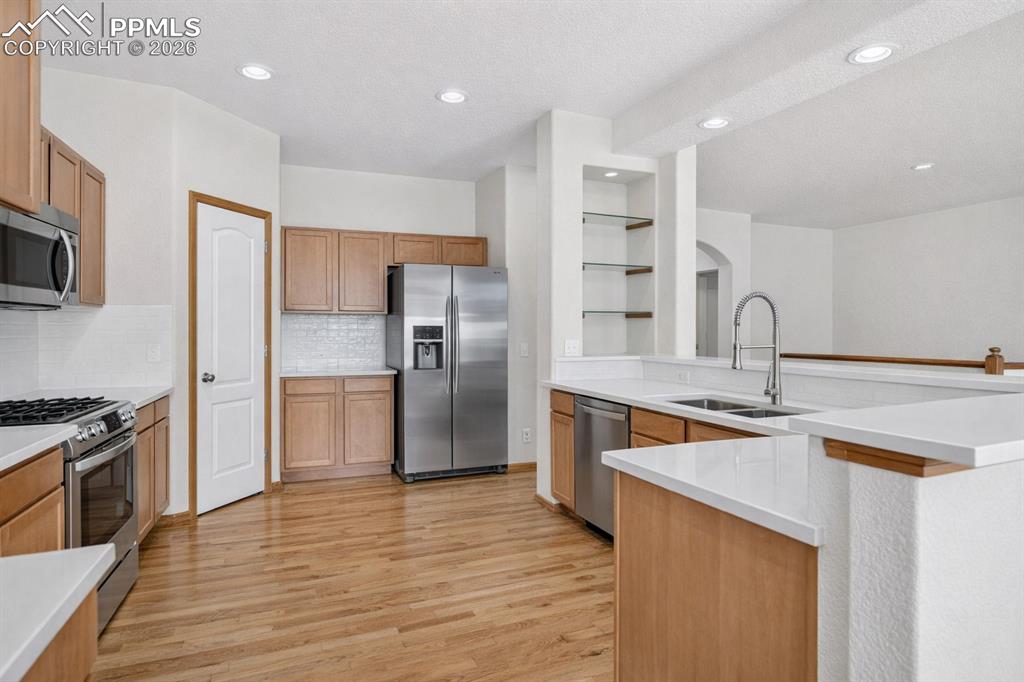 Image 6 of 22: Kitchen featuring stainless steel appliances, light wood-type flooring, bac