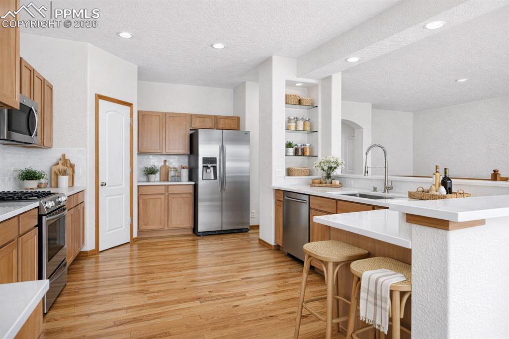 Image 7 of 22: Kitchen with stainless steel appliances, light wood-style flooring, a textu