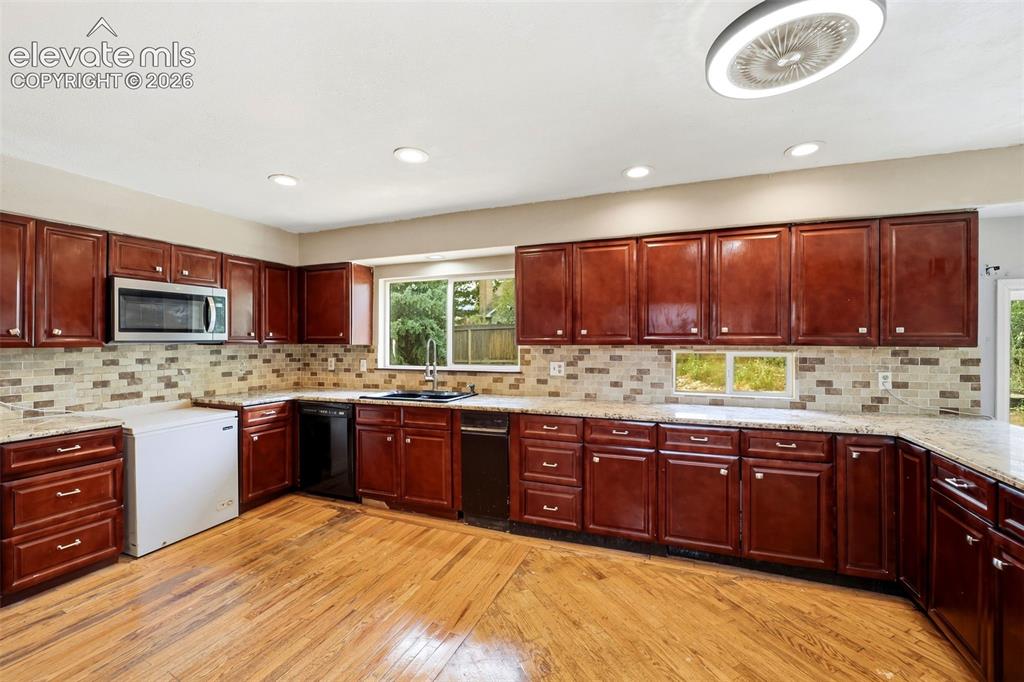 Image 11 of 34: Wood-finish flooring, recessed lighting, ample cabinetry, and a mosaic tile