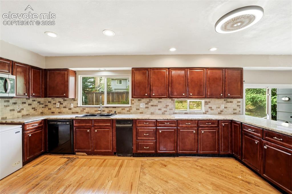 Image 16 of 34: Spacious kitchen featuring rich wood cabinetry, light-toned countertops, a 