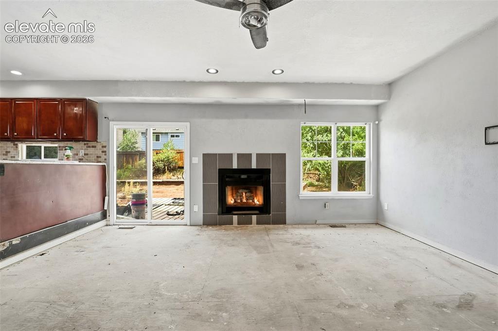 Image 19 of 34: Fireplace with tile surround, sliding glass door, recessed lighting, and a