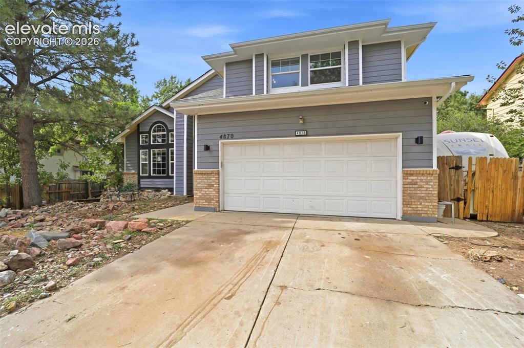 Image 2 of 34: Two-story exterior with gray siding, brick veneer accents, a two-car garage