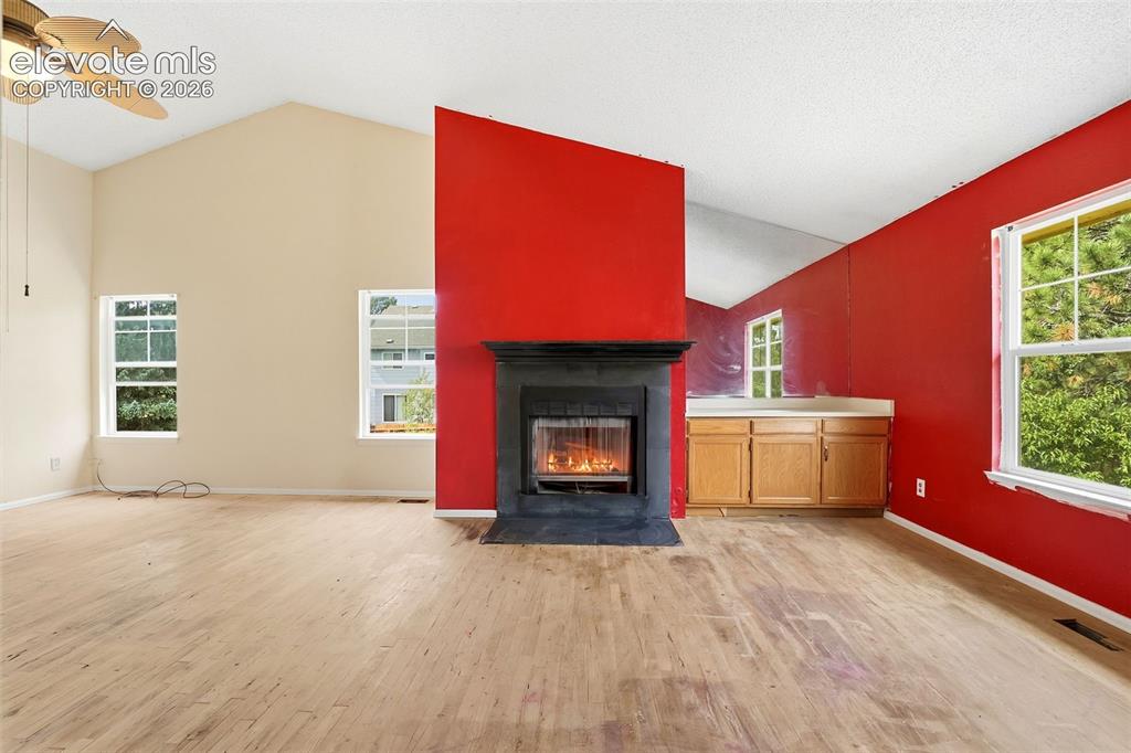 Image 21 of 34: Vaulted ceiling with a ceiling fan, light wood-finish flooring, and multipl