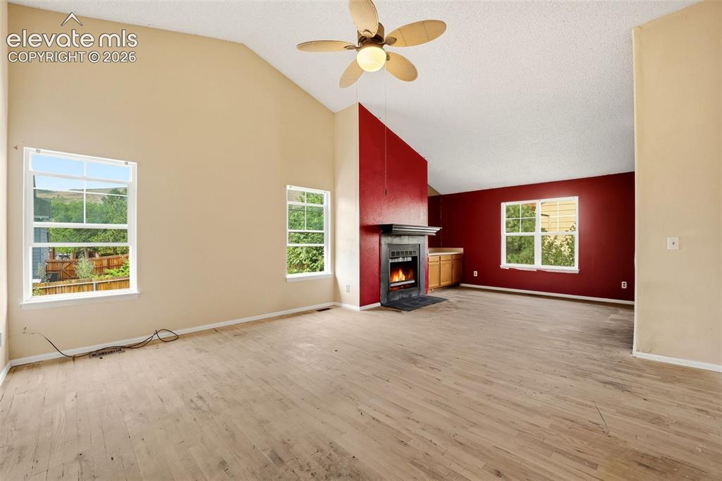 Image 22 of 34: Vaulted ceiling with an attached ceiling fan, floor-to-ceiling fireplace wi