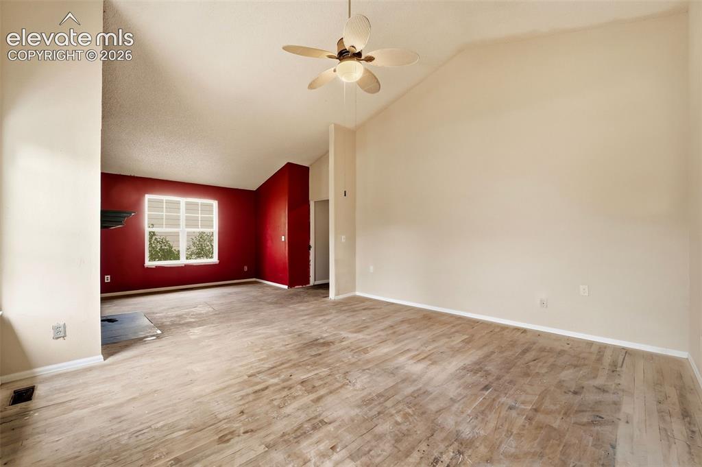 Image 24 of 34: Vaulted ceiling with a ceiling fan, wood-finish flooring, and a window with