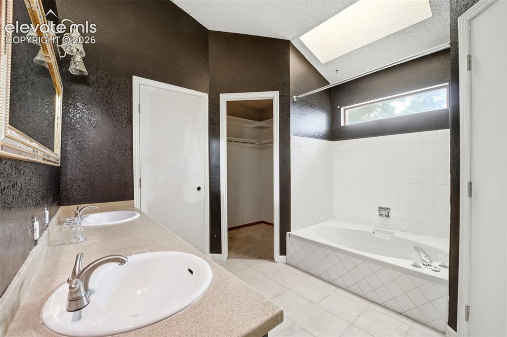 Image 26 of 34: Dual vanity with integrated sinks, built-in soaking tub with white subway t