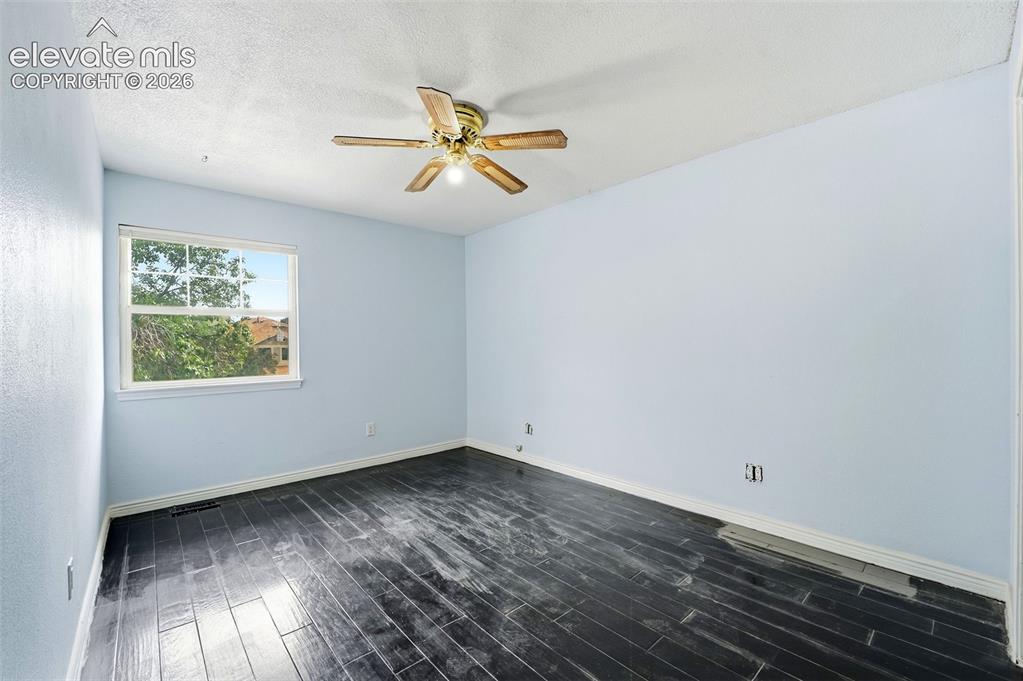 Image 29 of 34: Room with dark wood-finish flooring, light blue wall paint, and a ceiling f