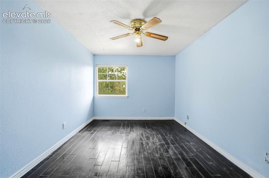 Image 30 of 34: Wood-finish flooring, light blue textured walls, and a ceiling fan with lig