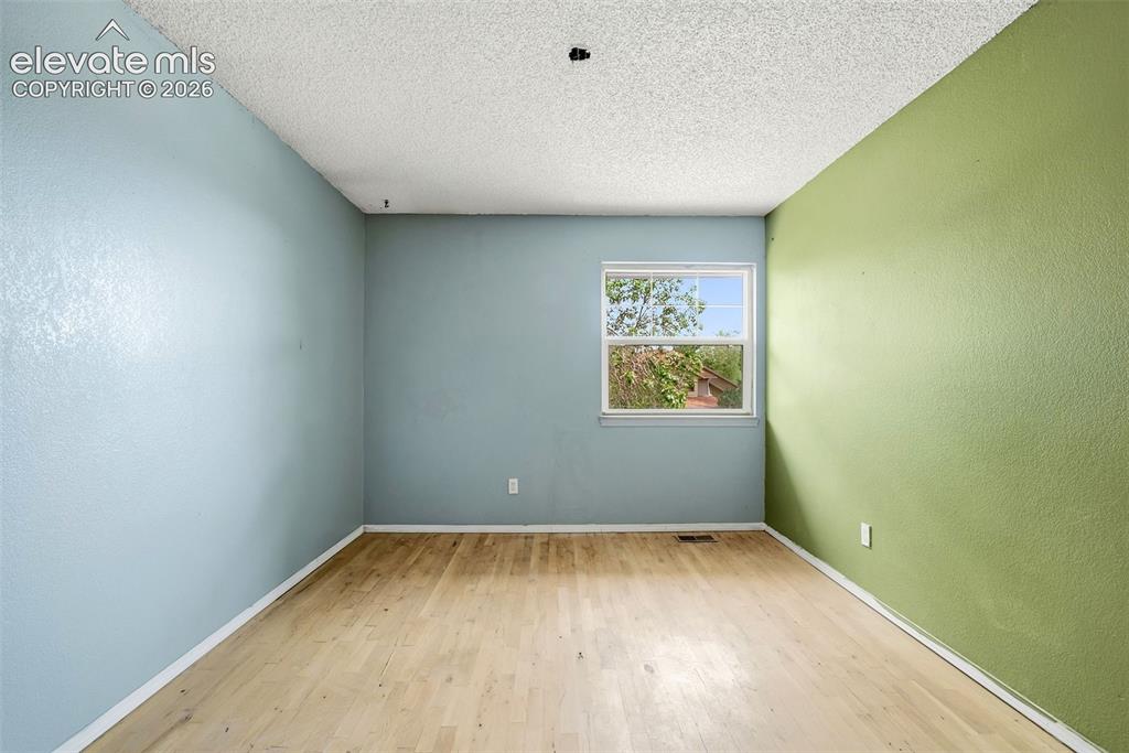 Image 32 of 34: Wood-finish flooring, textured walls, and a window providing natural light