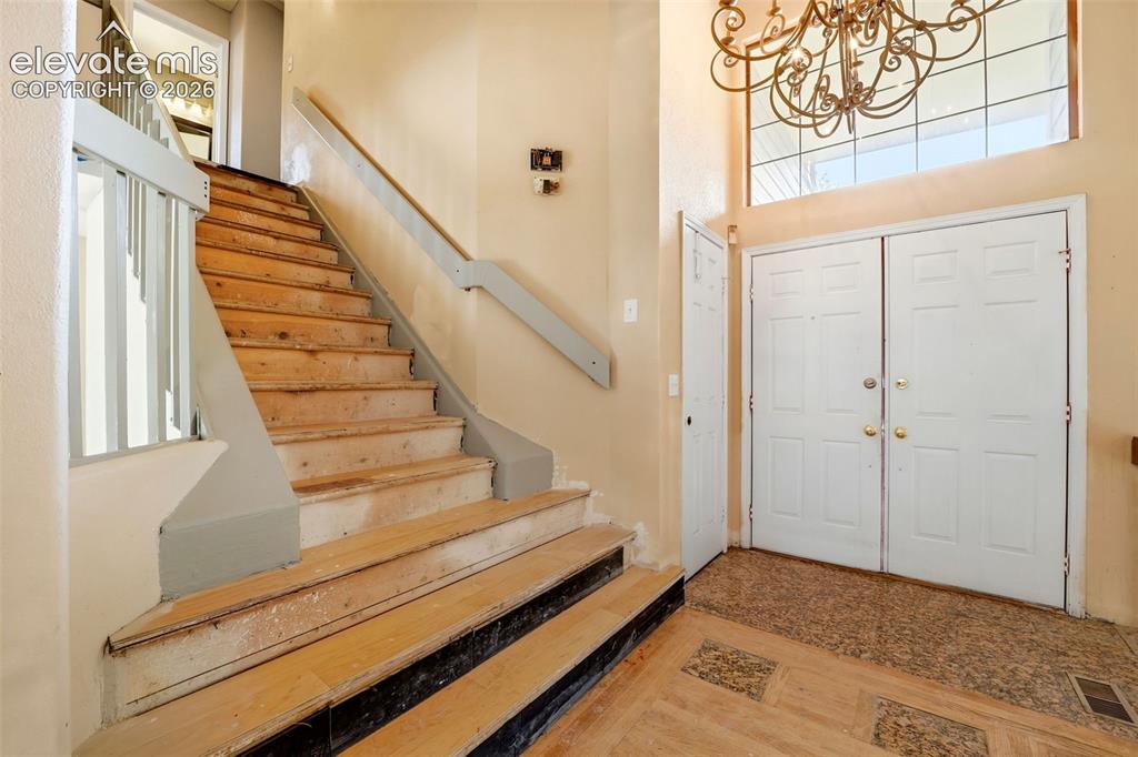 Image 4 of 34: Foyer featuring double entry doors, transom window, and an ornate chandelie