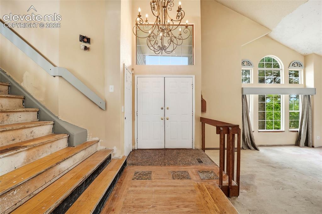 Image 5 of 34: Two-story foyer with double entry doors, wood-finish flooring, and an ornat
