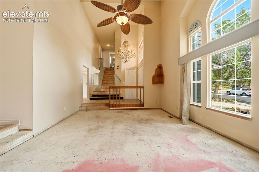 Image 6 of 34: Two-story entry with a ceiling fan, crystal chandelier, and staircase with 
