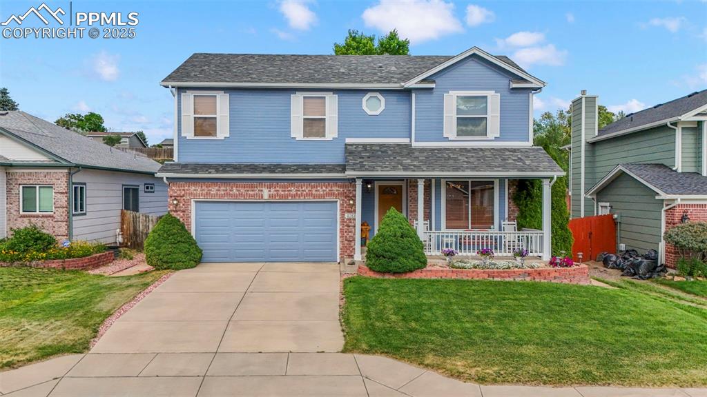 Caption: Traditional home with a porch, brick siding, concrete driveway, and a garage