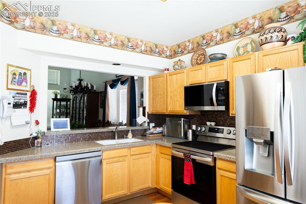 Image 11 of 48: Kitchen with appliances with stainless steel finishes, decorative backsplas