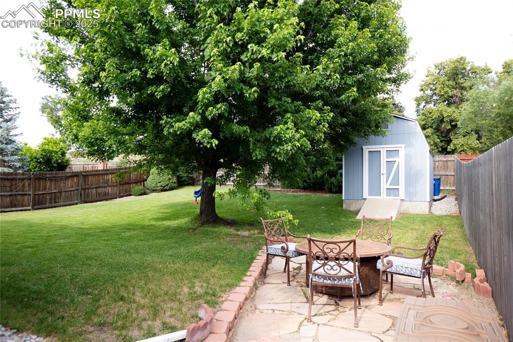 Image 23 of 48: Fenced backyard with a shed and a patio