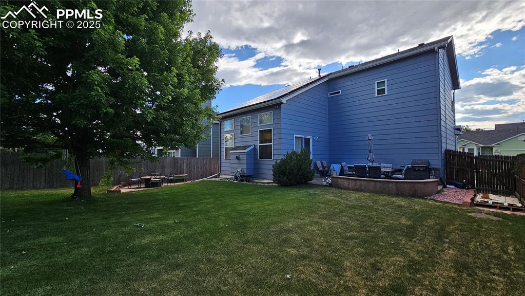 Image 24 of 48: Rear view of house featuring a fenced backyard, an outdoor fire pit, and a 