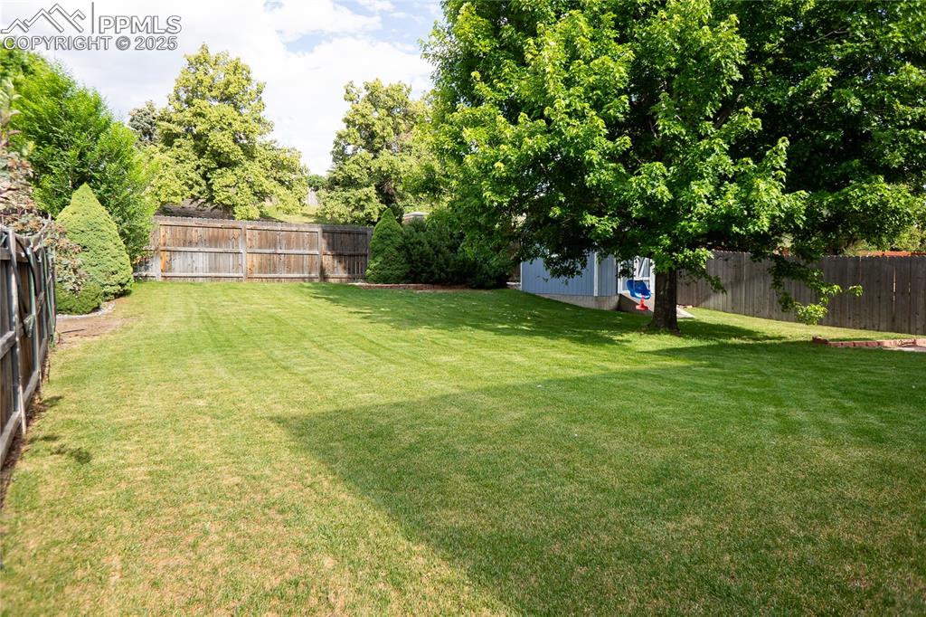 Image 26 of 48: Fenced backyard featuring a storage unit