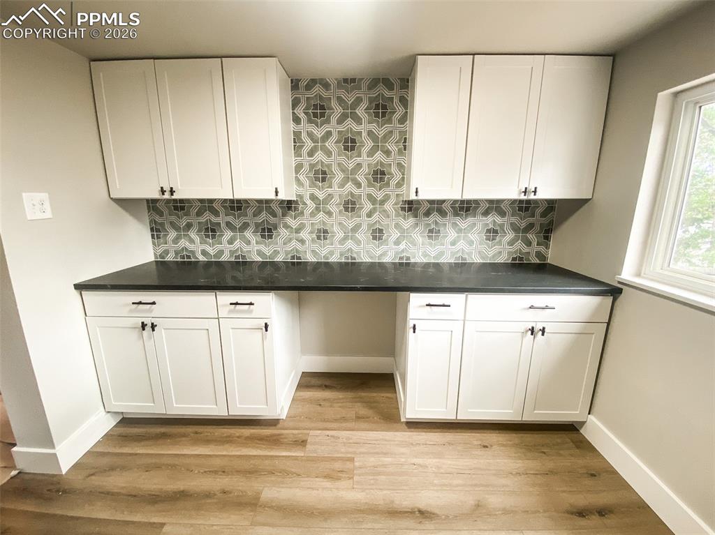 Image 3 of 24: Modern kitchen featuring white cabinetry, dark countertops, and a patterned