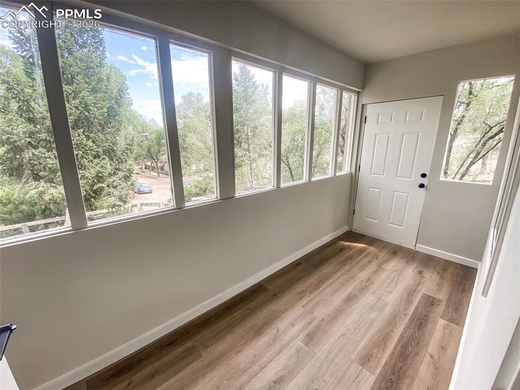 Image 5 of 24: Open-concept living space with wood-finish flooring, a contemporary chandel