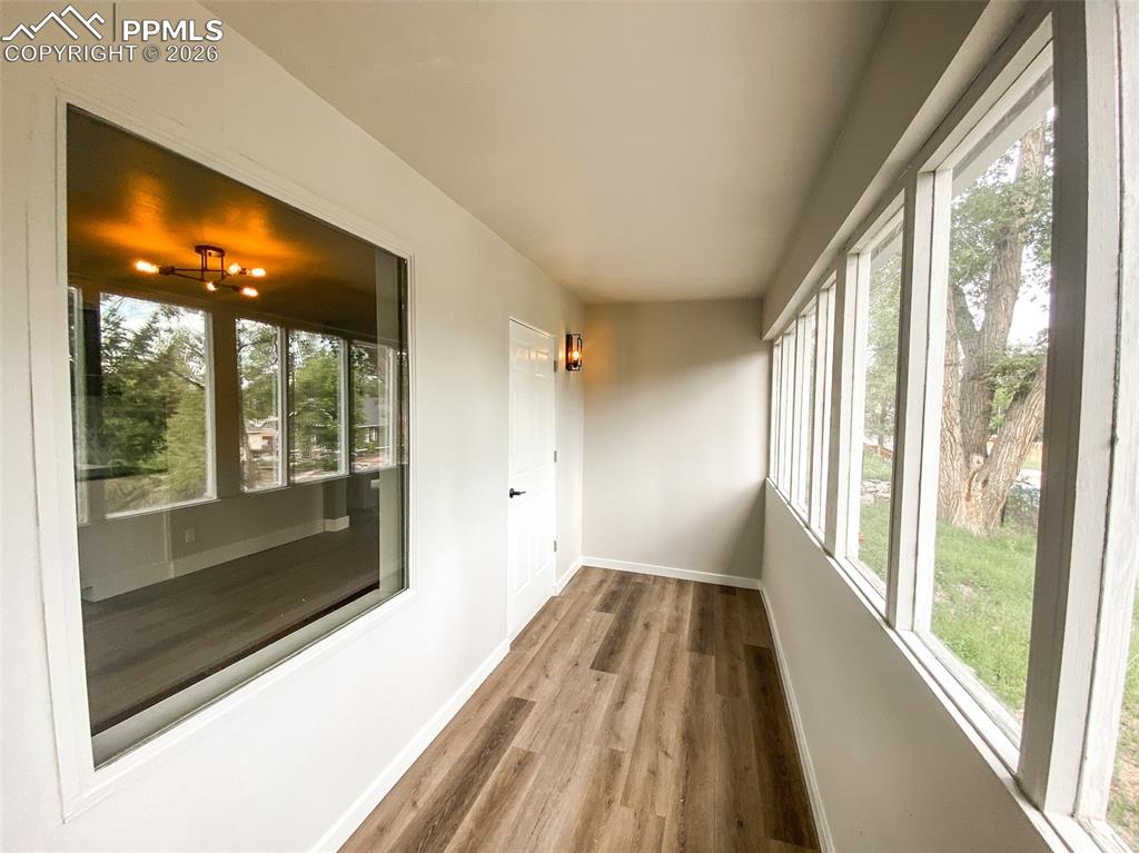 Image 6 of 24: Sunroom featuring a wall of windows, durable wood-finish flooring, a panele