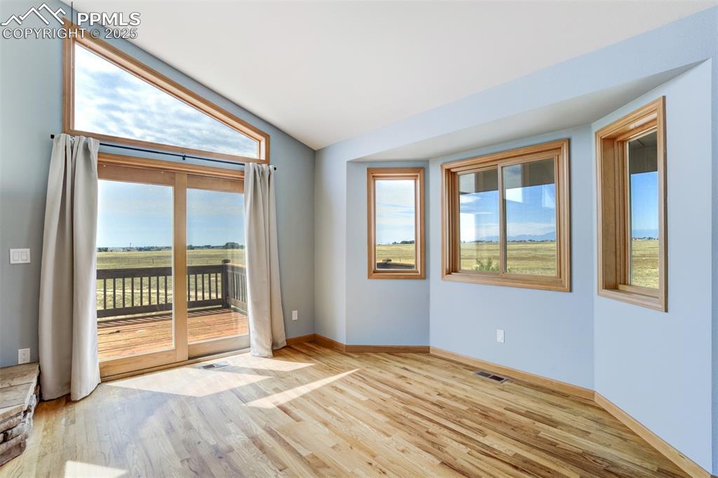 Image 12 of 50: Empty room with light wood-style floors, plenty of natural light, and vault