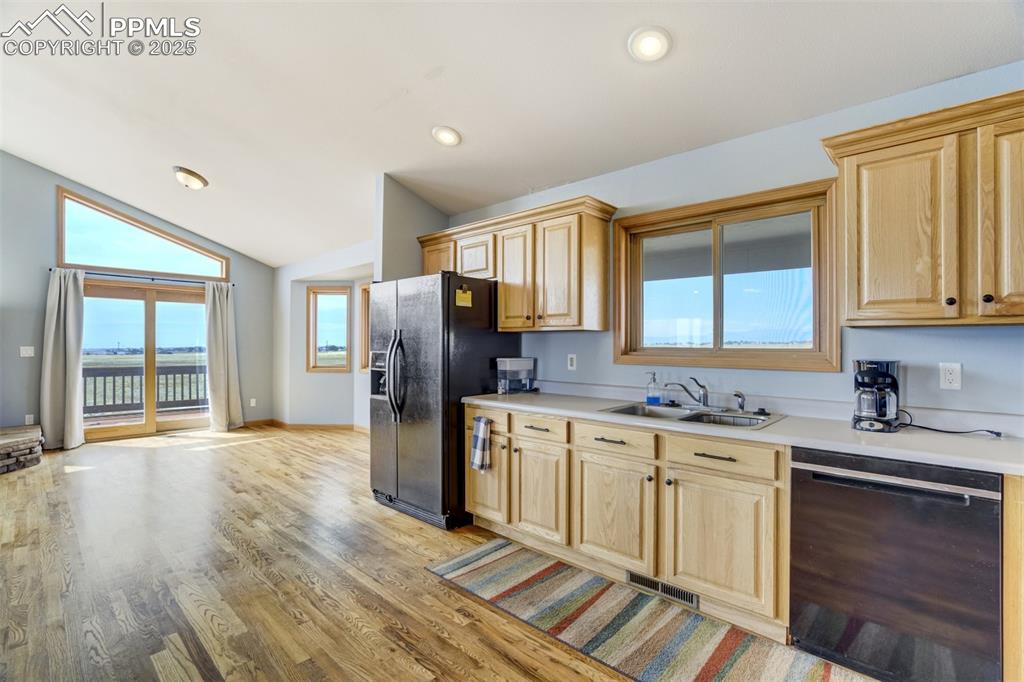 Image 16 of 50: Kitchen with light brown cabinets, black appliances, vaulted ceiling, light