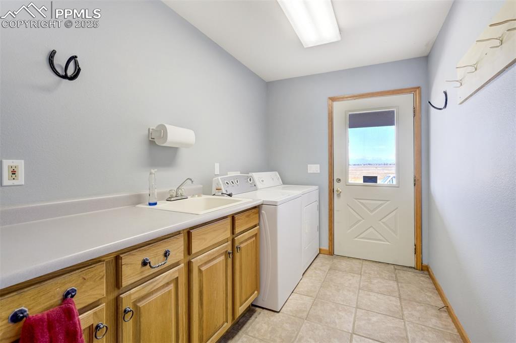 Image 18 of 50: Laundry area with independent washer and dryer, cabinet space, and light ti