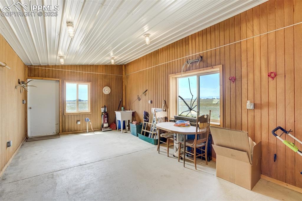 Image 38 of 50: Dining space with wood walls and concrete flooring