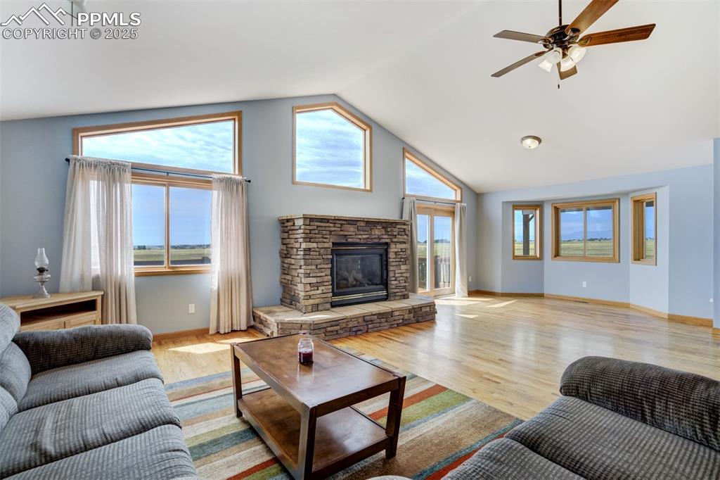 Image 7 of 50: Living area with a stone fireplace, healthy amount of natural light, light